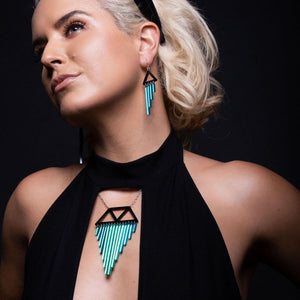 Person wearing Colour Pop Chimes Pendant Statement Necklace and Earrings in teal by Maine and Mara