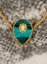A gold-colored bolo chain bracelet with a teal marbled agate pendant and a mirrored gold gemstone in the center, displayed on a textured background.