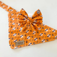 Load image into Gallery viewer, An orange pet bandana with a matching bow tie, featuring a repeating pattern of black crescent moons, white stars, and small brown bats. The bandana has a small brown leather patch on the corner with the brand name 'Puke' and a matching small round tag on the bow.