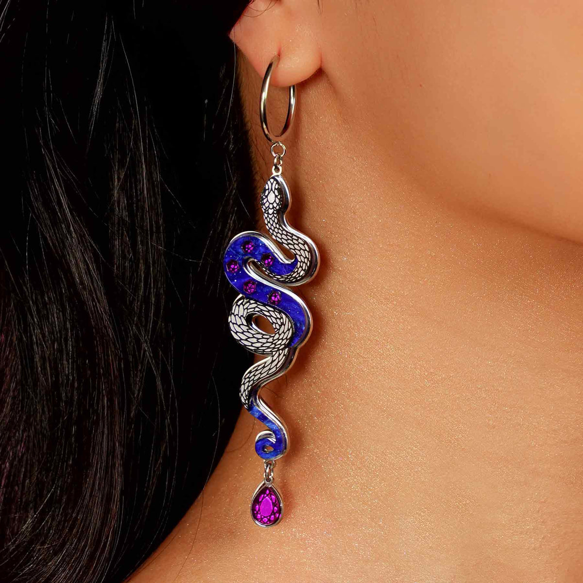 Snake hoop earring with blue and purple accents worn by a person