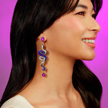 Load image into Gallery viewer, Woman wearing a unique earring with a purple gemstone on a purple background