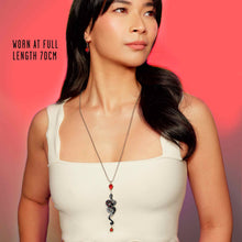Load image into Gallery viewer, Woman wearing a necklace with a red pendant against a pink background