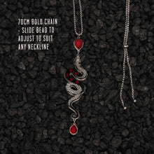 Load image into Gallery viewer, Necklace with snake design and red beads on a dark textured background