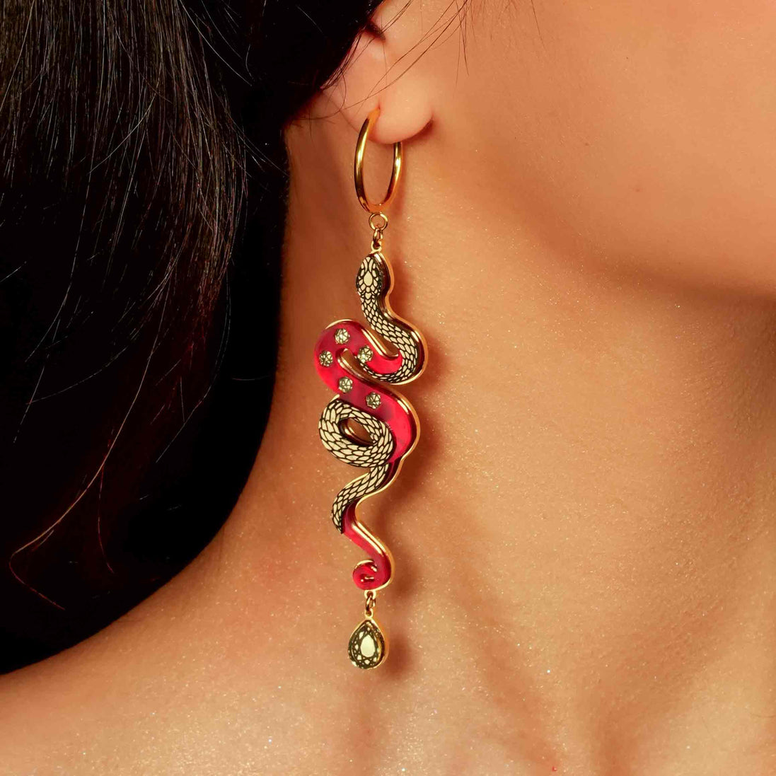 red and gold year of the snake gold hoop earrings on models ear