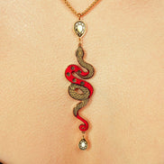 Snake-shaped pendant necklace on a person's neck against a beige background
