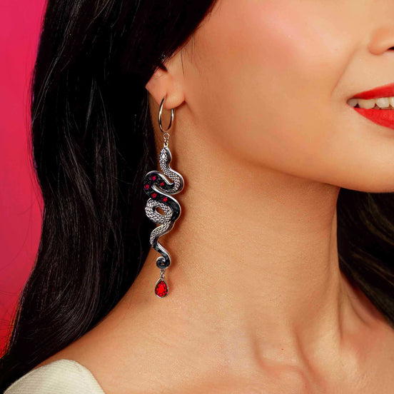 Snake-shaped earring on a model against a pink background