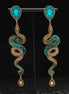Pair of snake-shaped earrings with turquoise and gold design on a black background