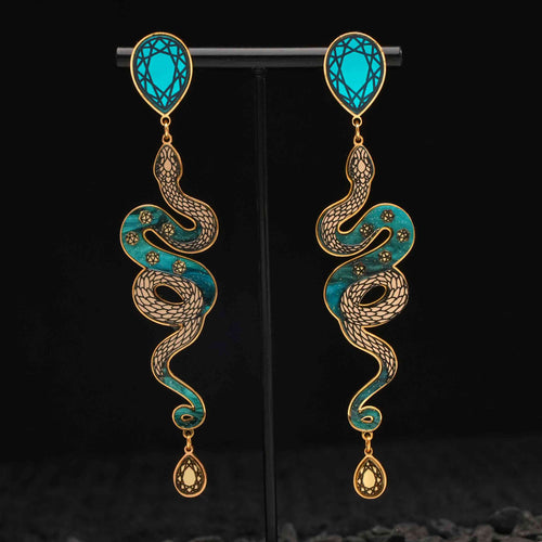 Pair of snake-shaped earrings with turquoise and gold design on a black background
