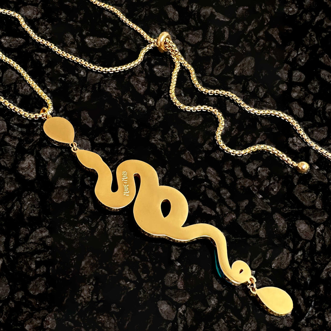 Gold snake-shaped necklace on a dark textured background
