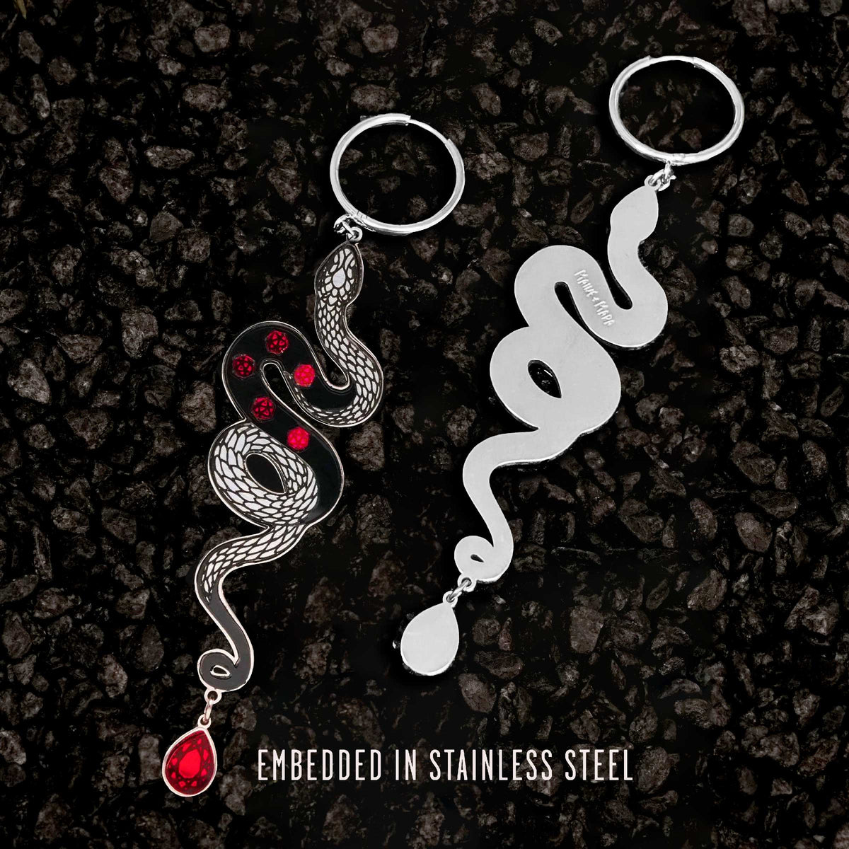 Pair of snake-shaped hoop earrings on a dark textured background with text 'Embedded in Stainless Steel'.