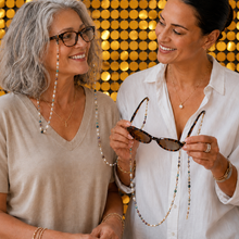 Load image into Gallery viewer, Two women smiling and looking at long beaded necklaces and sunglasses. One woman has gray hair and glasses, wearing a beige top, and the other has dark hair and wears a white button-up shirt.