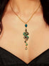Gold and green snake-shaped necklace on a person wearing a black top.