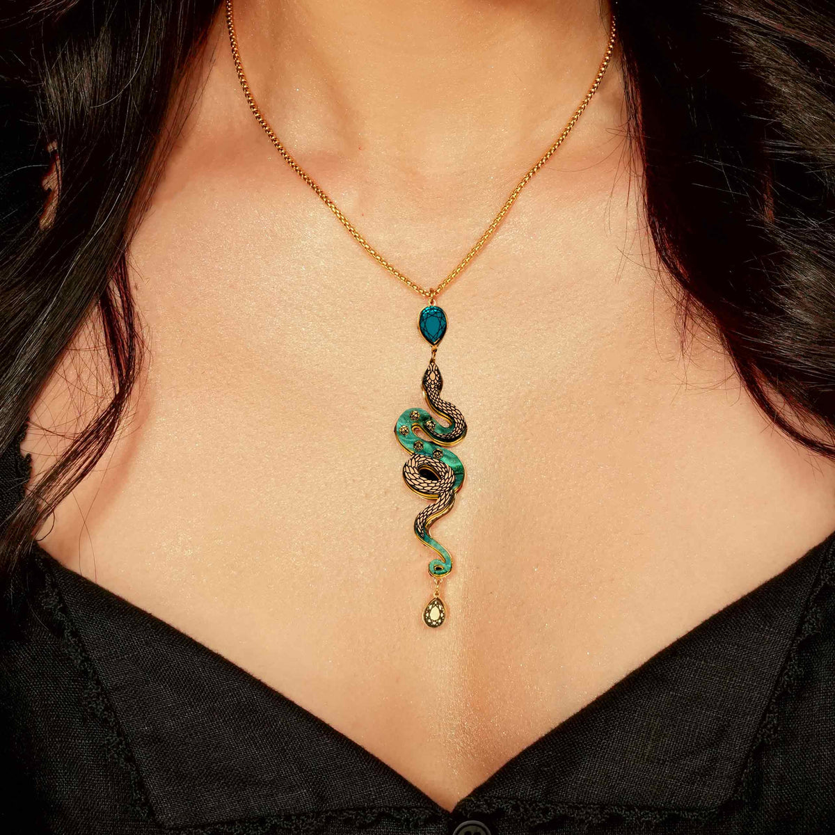 Gold and green snake-shaped necklace on a person wearing a black top.