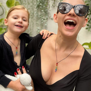Person And Child Laughing While Wearing Matching Maine And Mara Glittery Pride ANJA RAINBOW NECKLACES For Adults and Children